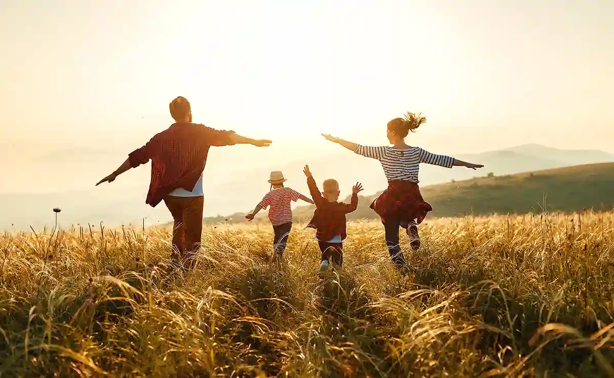 une famille heureuse court dans un champ de blé, l'image symbolise la liberté que peut apporter un rachat de credit pour réaliser les projets d'une famille